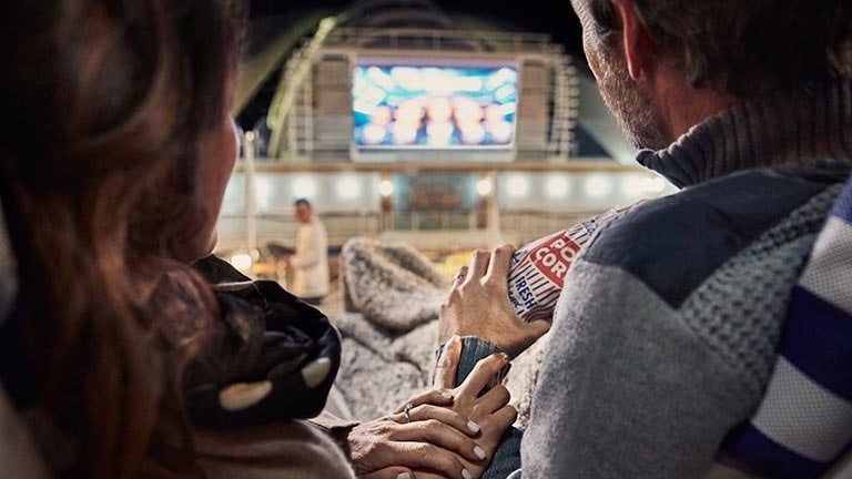 couple sitting together, watching a movie on outdoor movie screen