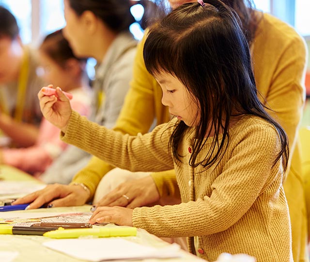 young girl creating artwork while sitting at a table