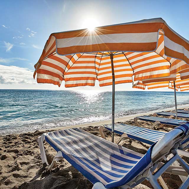 Beach Chairs With Orange And White Umbrellas On A In The Caribbean