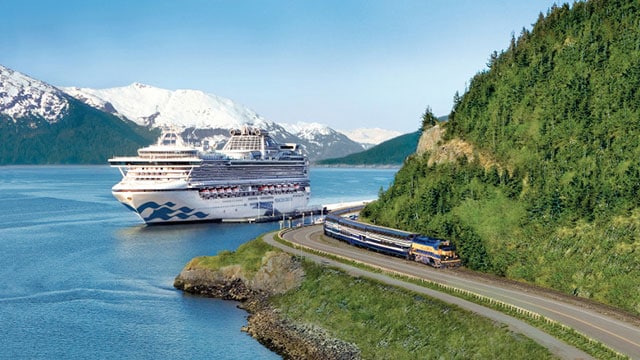Direct-to-the-Wilderness Alaska Rail Service train passes by docked Princess Cruises cruise ship in Alaska