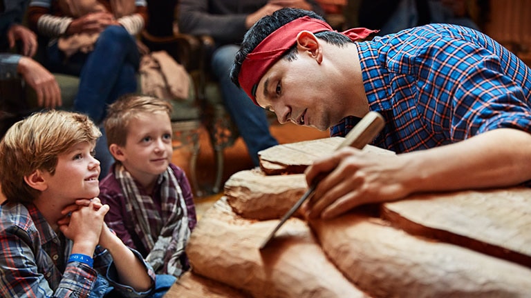 Artist Kenneth White on board Princess showing a totem carving exhibition to a young group