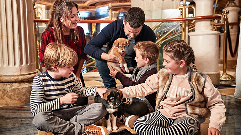 A family taking pictures with some of Skagway’s newest sled dogs on Alaska cruise