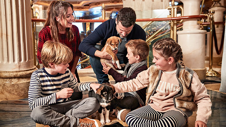 A family taking pictures with some of Skagway’s newest sled dogs on Alaska cruise