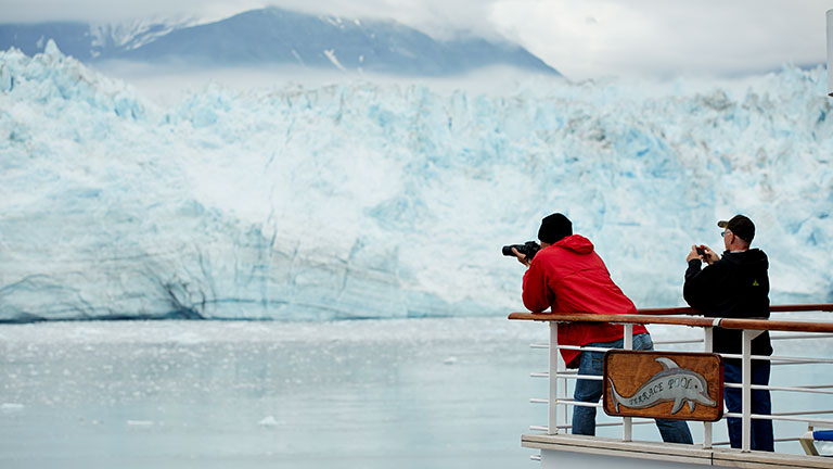 Two men taking a photos of hubbard glacier on Alaska cruise