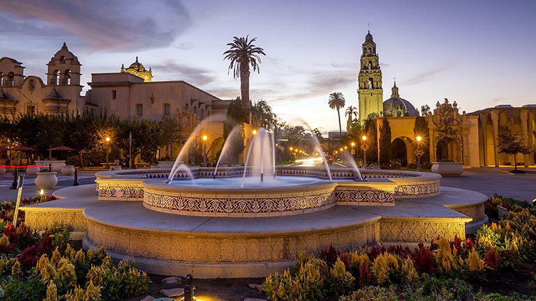 fountain in san diego at dusk with palm trees and buildings
