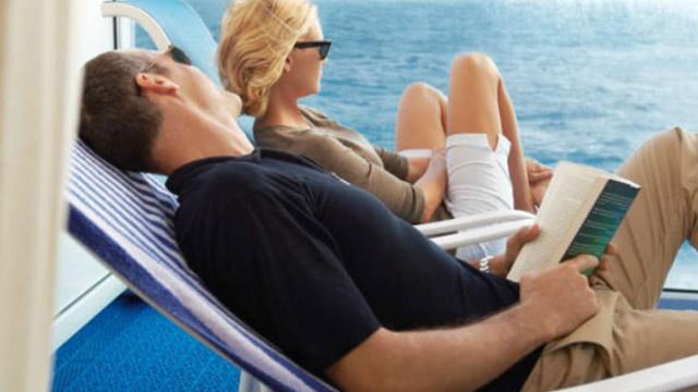 a man and woman sitting in lounge chairs onboard a cruise ship