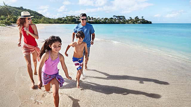Family on the beach, running through the shallow water 