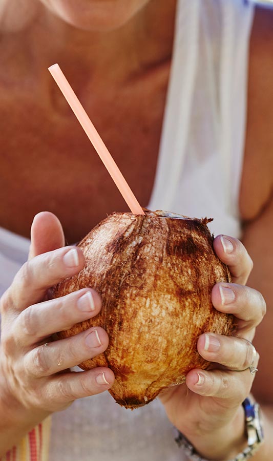 person holding a drink in coconut vessel
