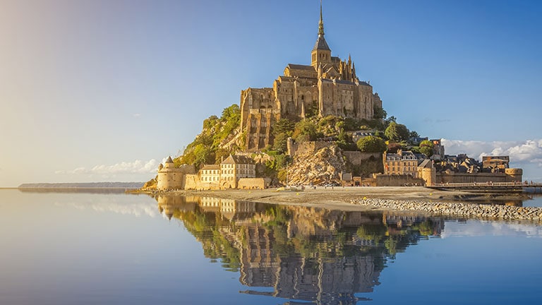 Mont Saint Michel - a medieval building with reflection in a surrounding body of water