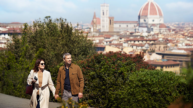 A couple holding hands with Santa Maria del Fiore Catheral behind them