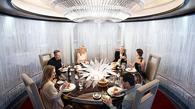A group of people eating and drinking wine at a round table
