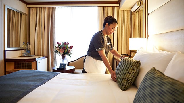 a stateroom attendant making a bed