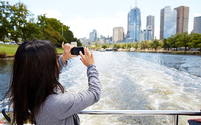 Women taking a photo from a ship looking out to the Sydney skyline - play video