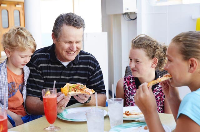 Father and three kids eating pizza