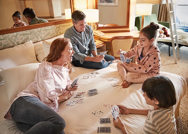 Family of four relaxes in their stateroom, playing Go-Fish