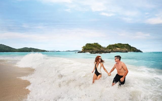 Couple enjoying an ocean wave in the Caribbean on a Princess romantic cruise