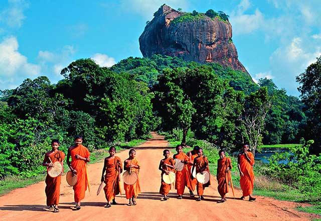 children walking down road in Sri Lanka with Lion Rock in the background