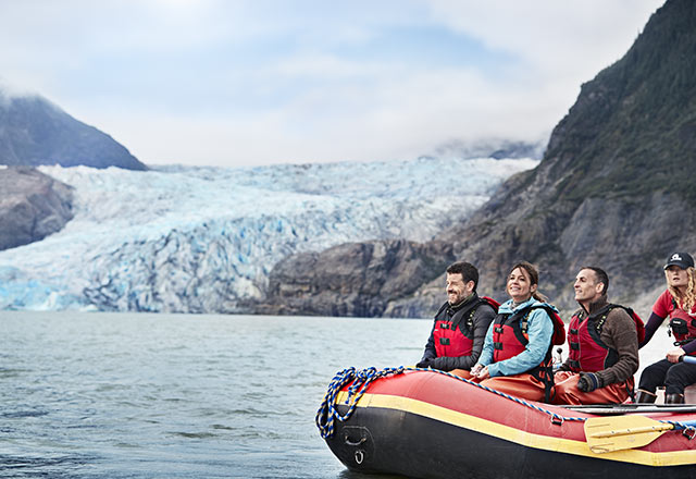 people on raft in bay surrounded by glaciers